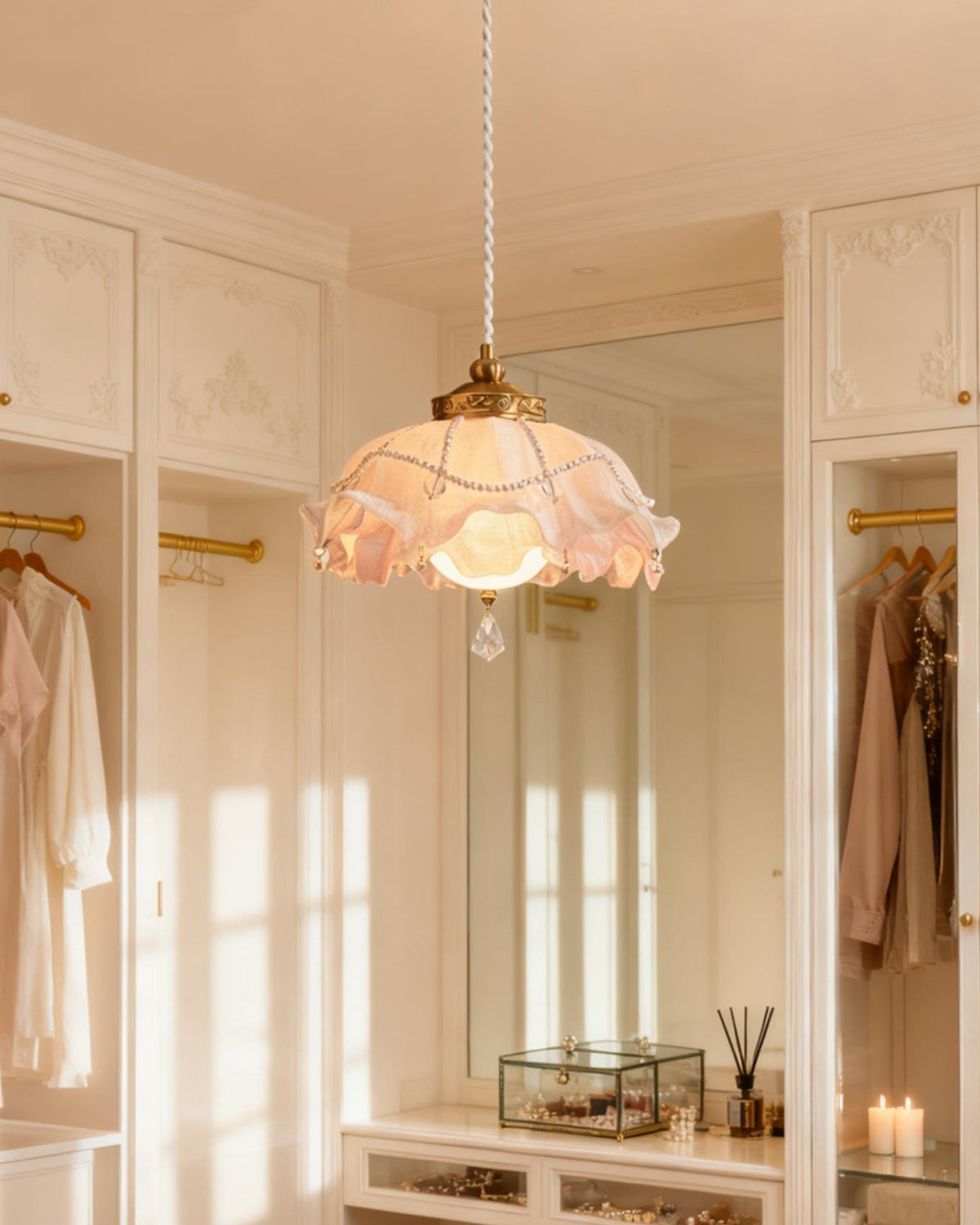 A Clérachic pendant glowing in a white dressing room with panelled wardrobes, hanging robes and a tall mirror behind it.