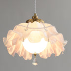 Looking up into this Clérachic pendant: the frilled shade glows around a round bulb, with pearl beads and a faceted crystal drop below.
