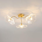 The Clérachic ruffled flower ceiling light in clear glass, three brass gooseneck arms fanning from a round canopy.