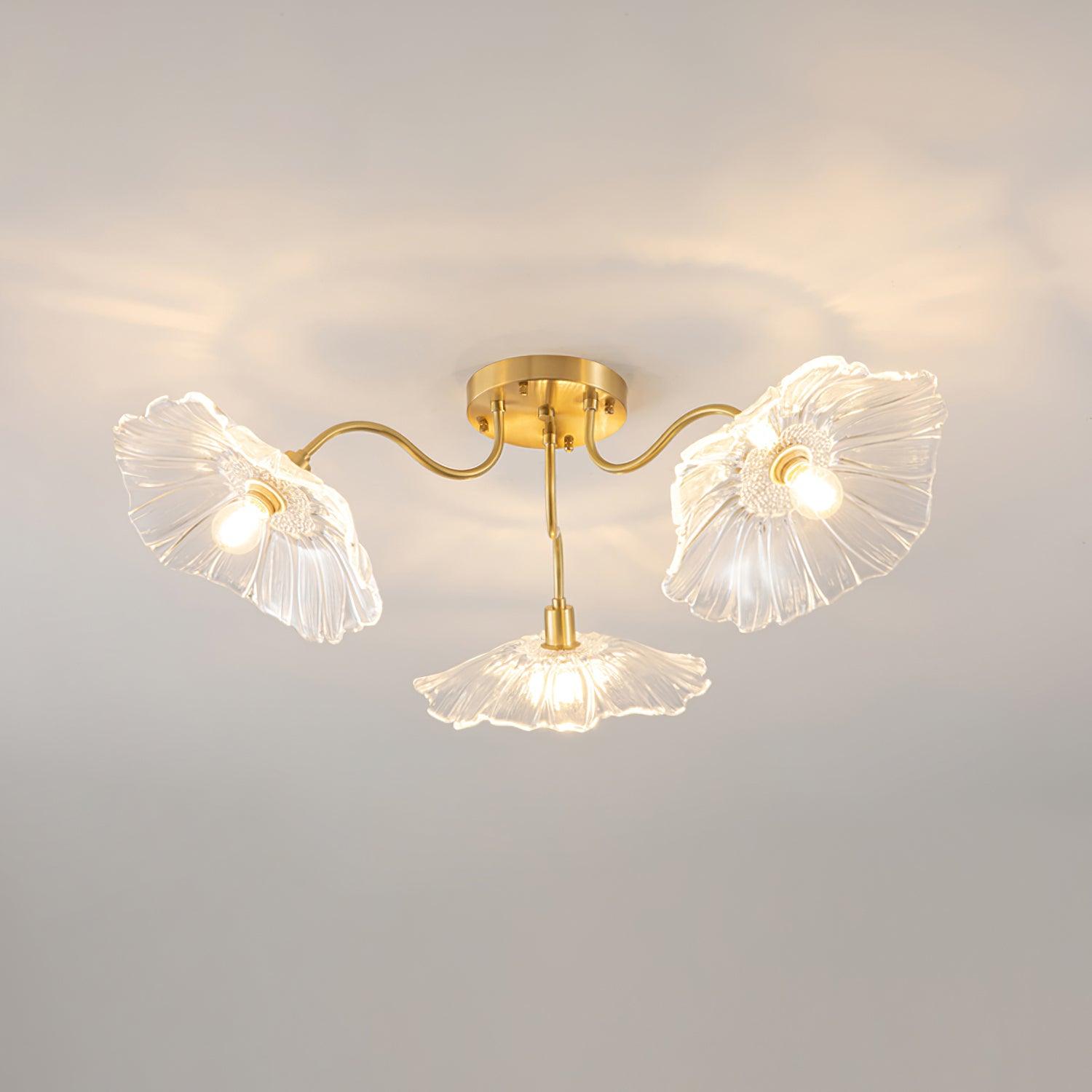 The Clérachic ruffled flower ceiling light in clear glass, three brass gooseneck arms fanning from a round canopy.