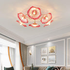 The pink glass Clérachic ceiling light lights a bedroom with a rust upholstered headboard and grey pillows.