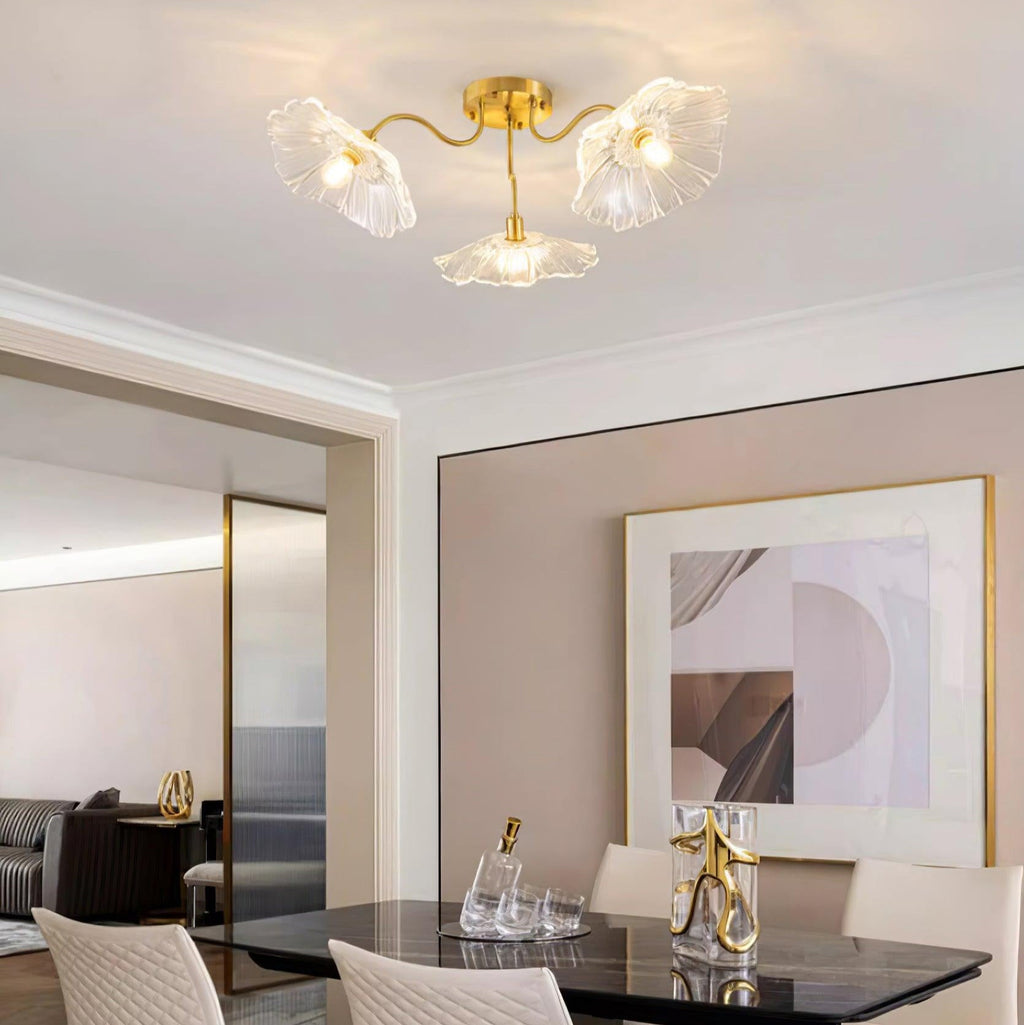 Three clear glass flowers on the Clérachic ceiling light hang over a mirrored console beside a dining table.