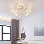 Clérachic's clear glass ceiling light lights a bedroom with taupe curtains and a round leather-strap mirror.