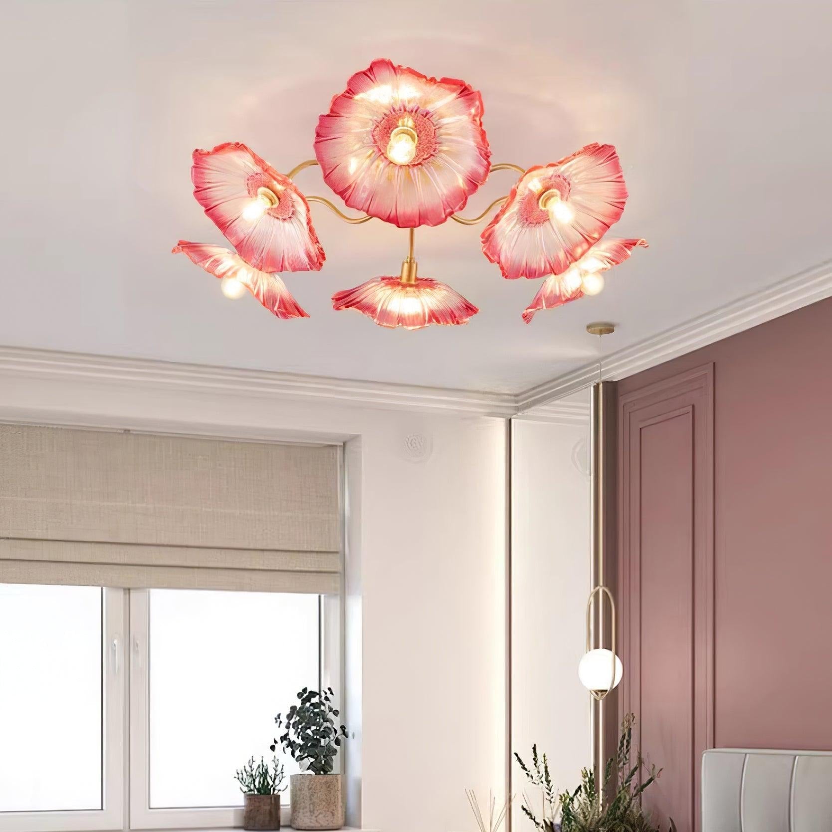The pink glass Clérachic ceiling light sits near a rose-pink door in a room with linen roman blinds and potted plants.