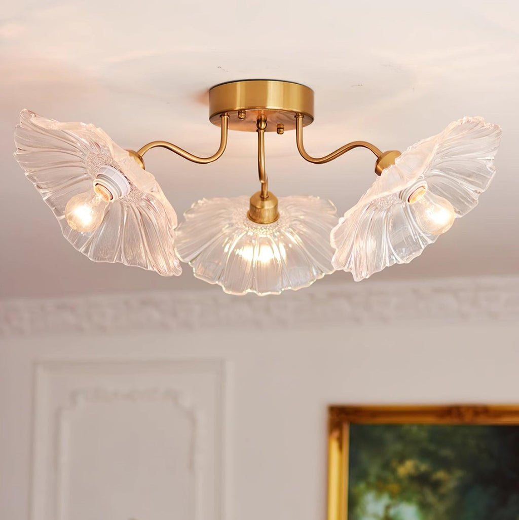 A close view of the Clérachic clear glass ceiling light beneath ornate crown moulding and a gilt-framed painting.