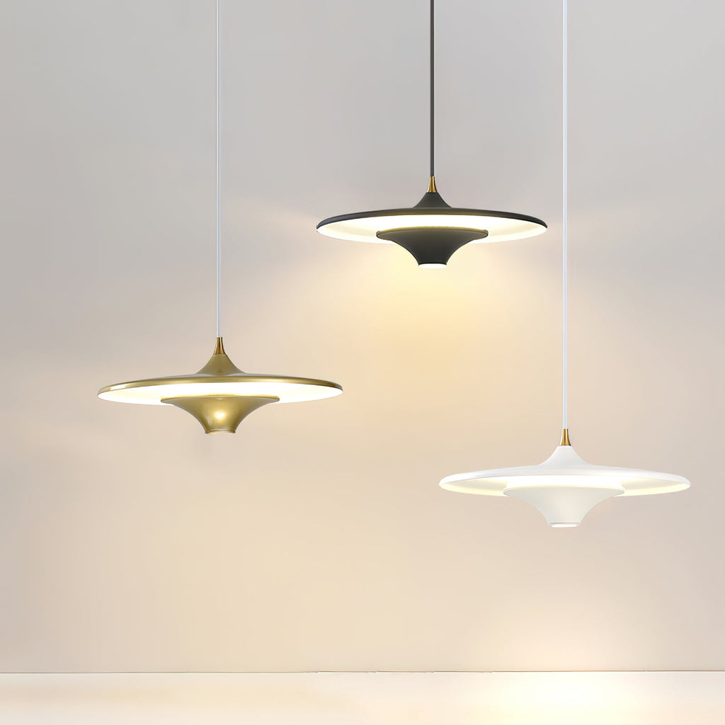 Gold, black and white Clérachic saucer pendants hang at different heights against a pale grey wall.