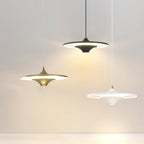 Gold, black and white Clérachic saucer pendants hang at different heights against a pale grey wall.