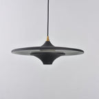 Matt black Clérachic saucer pendant with a brass collar, seen from the side against a light grey wall.