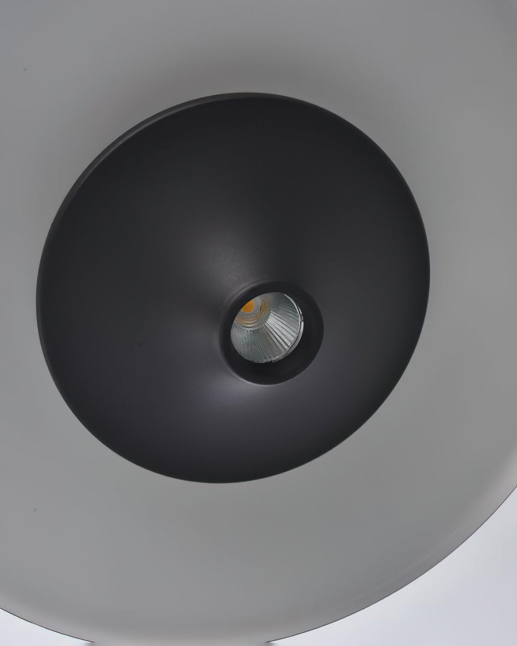 Close view of the recessed LED spot at the centre of the black cone on this Clérachic pendant.