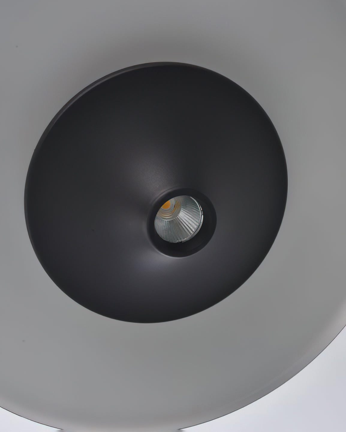 Close view of the recessed LED spot at the centre of the black cone on this Clérachic pendant.