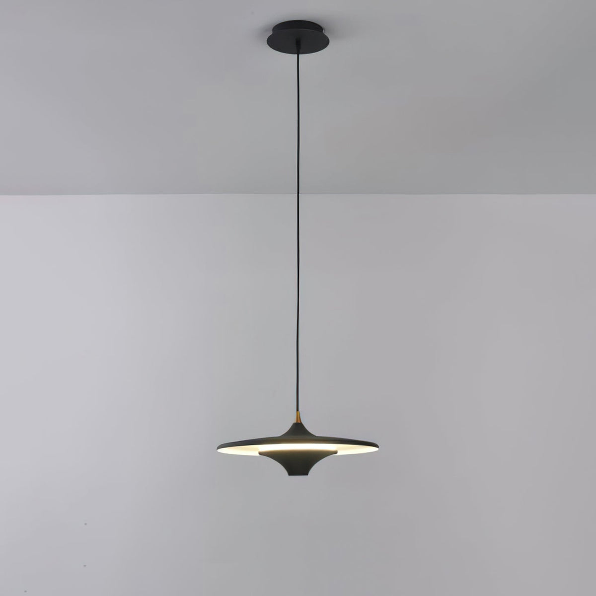Black Clérachic saucer pendant lit, hanging on a black cord from a black canopy against a pale grey wall.