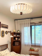 A second view of this Clérachic ceiling light in a bedroom, its scalloped shade glowing above a wooden bed frame and a small shelf.