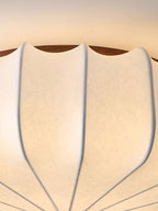 Close view of the ribbed fabric and the wooden rim on the scalloped shade of this Clérachic ceiling light.