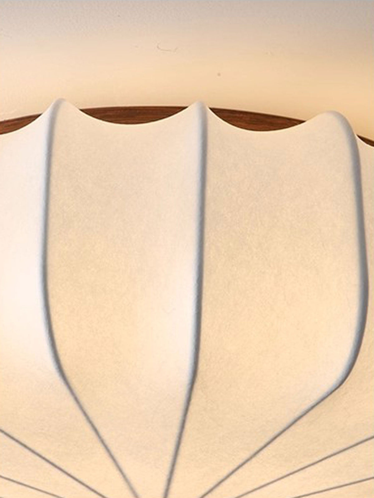 Close view of the ribbed fabric and the wooden rim on the scalloped shade of this Clérachic ceiling light.
