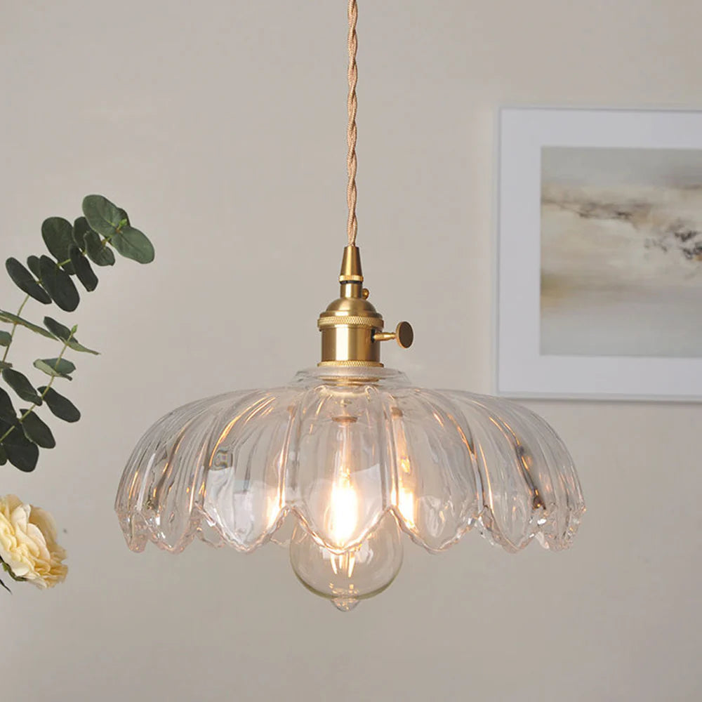 The Clérachic Scalloped Flower Glass Pendant Light in clear ribbed glass, hung beside framed art and a eucalyptus sprig in a calm room.