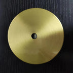 The flat round brass ceiling canopy of the Clérachic Scalloped Flower Glass Pendant Light, centre hole visible, on dark wood.