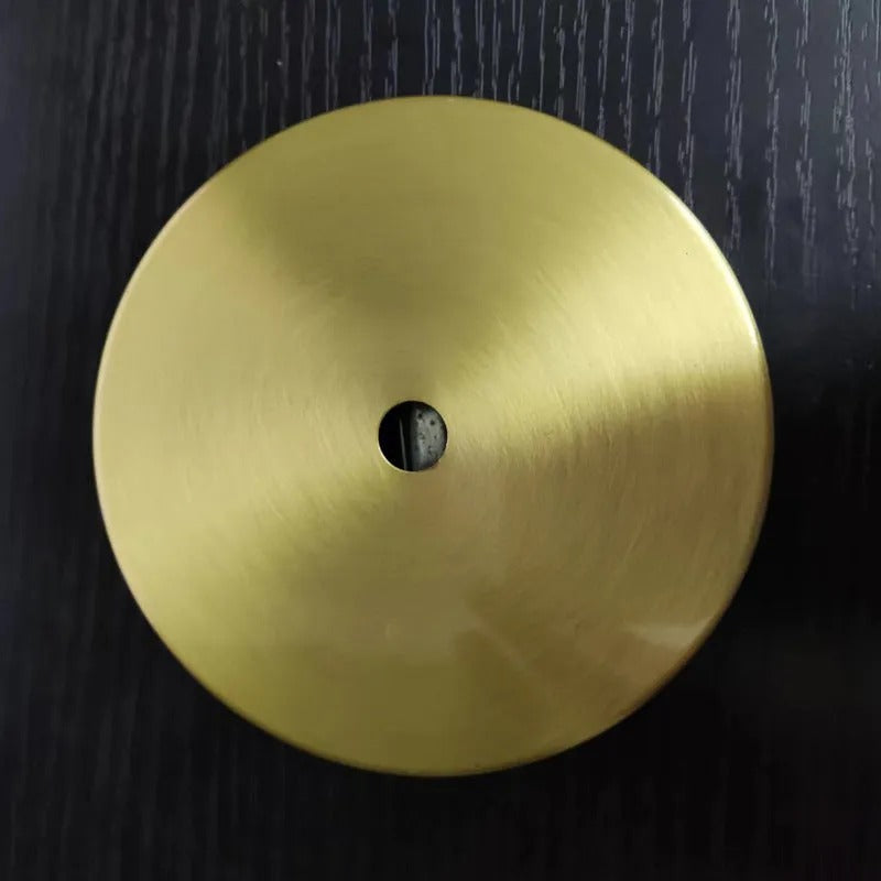 The flat round brass ceiling canopy of the Clérachic Scalloped Flower Glass Pendant Light, centre hole visible, on dark wood.
