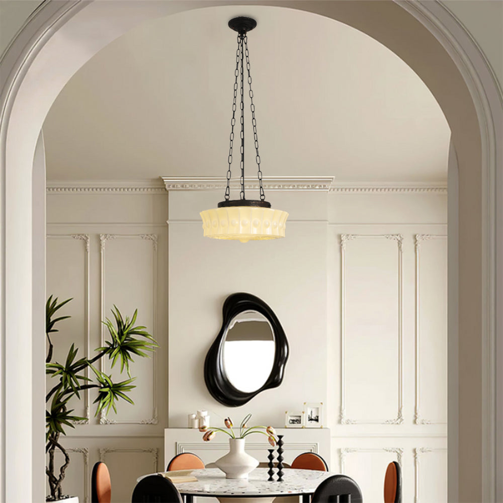 A beige Clérachic scalloped glass dome pendant light glowing over a round dining table, seen through an arched doorway