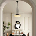 A beige Clérachic scalloped glass dome pendant light glowing over a round dining table, seen through an arched doorway