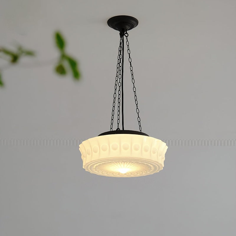 The Clérachic scalloped glass dome pendant light lit against a pale wall, its pressed rosette glowing warm at the centre of the shade