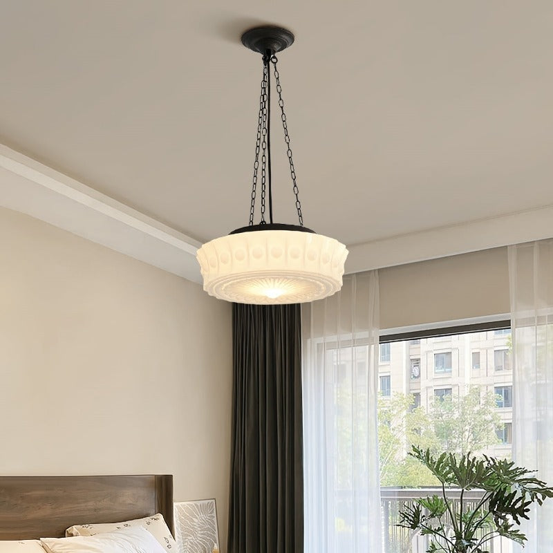 Clérachic scalloped glass dome pendant light lit above a wooden bed, with sheer curtains and a balcony window behind