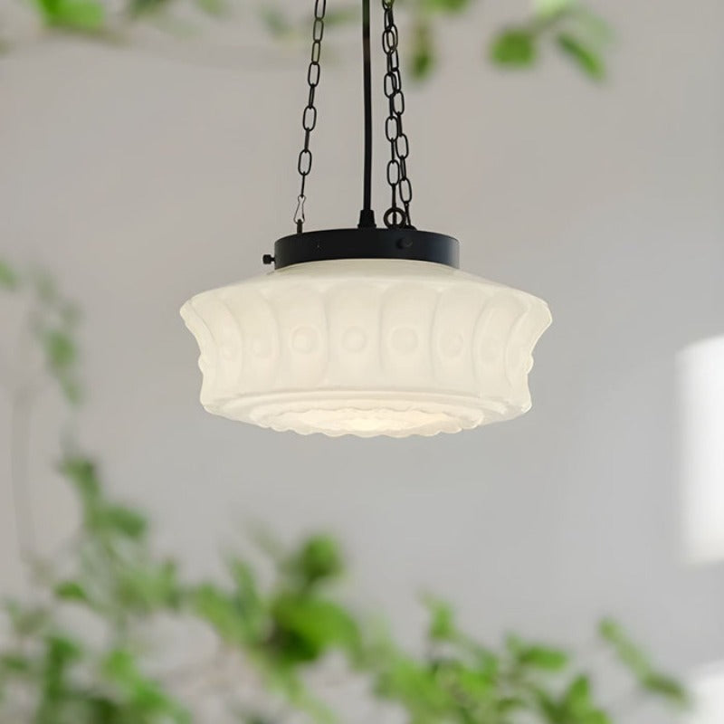 Side view of the white Clérachic scalloped glass dome pendant light, its fluted panels and round bosses framed by trailing greenery
