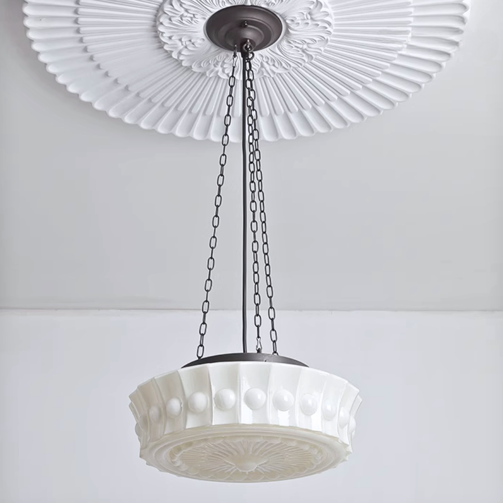 Close view of the white Clérachic scalloped glass dome pendant light below a large fluted plaster ceiling medallion