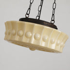 Angled detail of the beige Clérachic scalloped glass dome pendant light, raised bosses ringing the shade under its dark collar