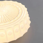 Close crop of the beige Clérachic scalloped glass dome pendant light, the scalloped rim and radiating rosette in warm ivory glass