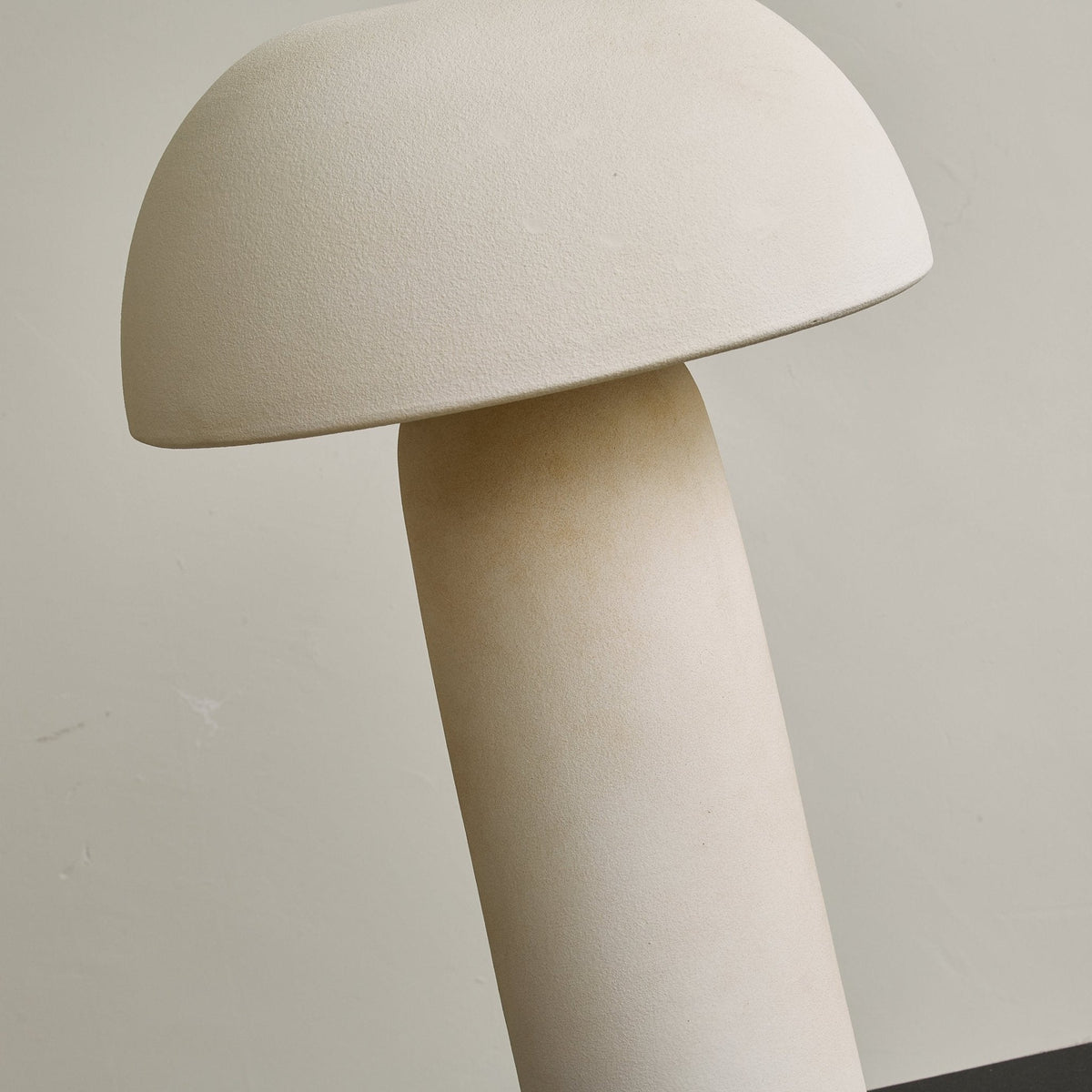 Close, tilted view of the unlit dome and the matt column, showing the speckled ceramic surface of this Clérachic table lamp.