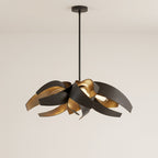 Clérachic sculptural chandelier in black, its folded steel ribbons matte black outside and warm brushed gold within, lit by LEDs hidden at the centre of the cluster