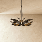 The Clérachic sculptural chandelier in black and gold, a wider double cluster of steel ribbons on cables and a canopy.