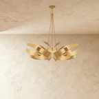 The Clérachic sculptural chandelier in gold, its steel ribbons spread into a double cluster on cables and a canopy.