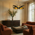 The Clérachic black and gold sculptural chandelier lit above a living room with terracotta sofas and a chess set.