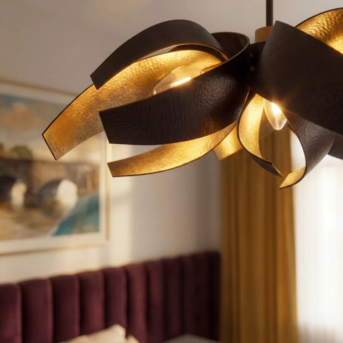 Close detail of the Clérachic black and gold sculptural chandelier, its steel ribbons curved around a glowing bulb.