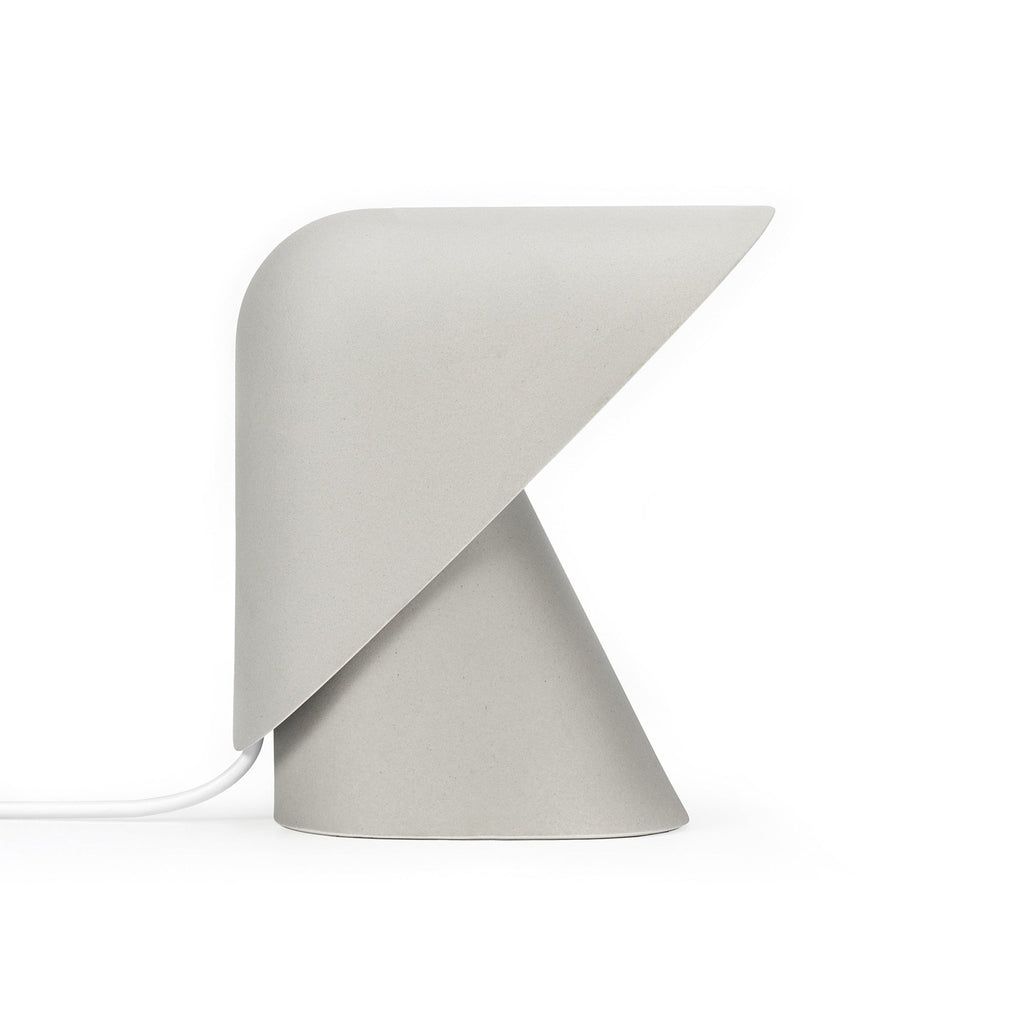Grey Clérachic table lamp on a white backdrop, with a speckled matt finish, a folded shade and a white cord at the left.