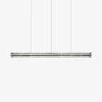 Clear segmented glass linear chandelier from Clérachic hanging on three fine cables against a plain white backdrop.