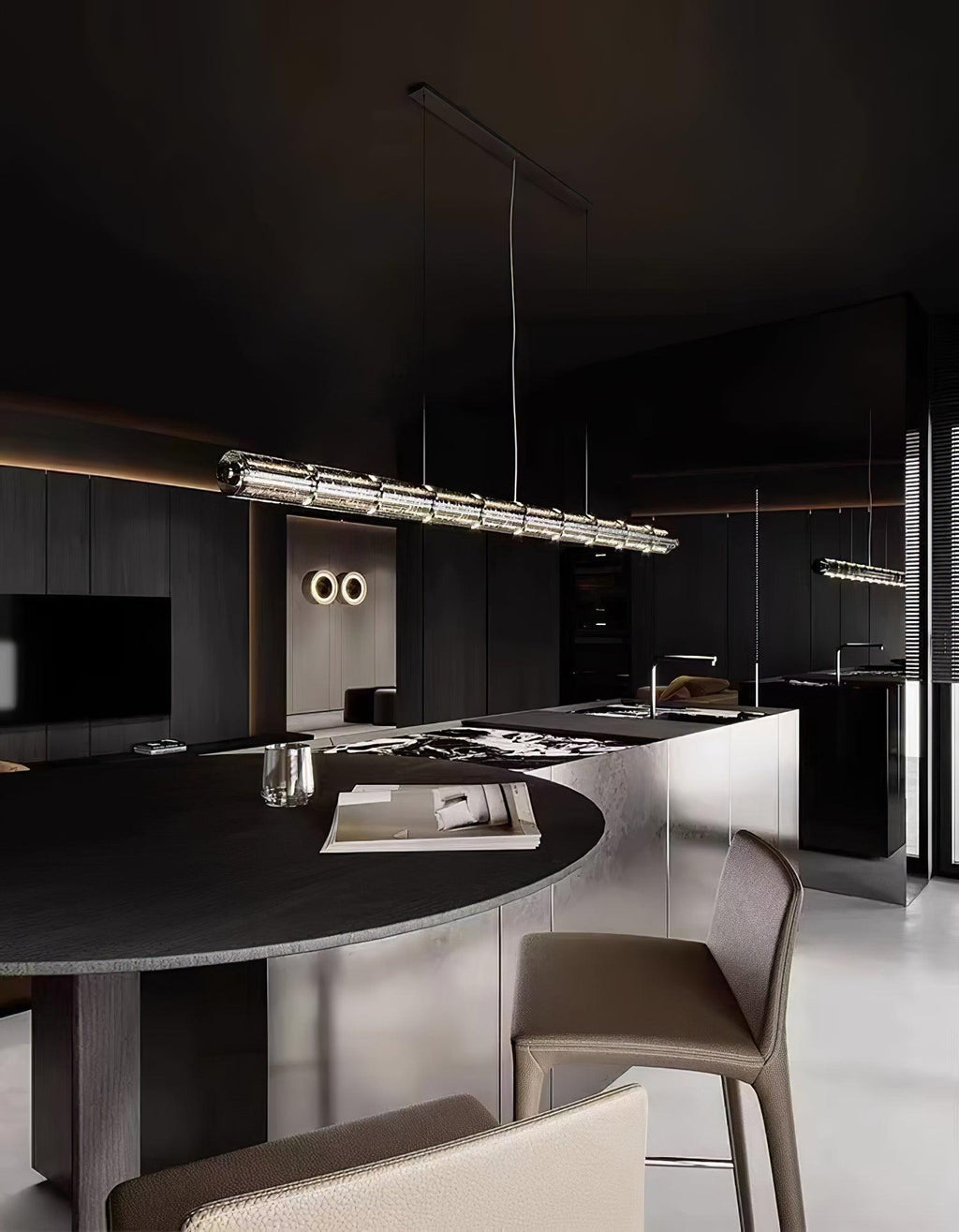 A Clérachic glass-segment chandelier lit over a round dark dining table in a moody kitchen with leather-seated stools.