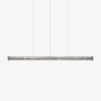 Long segmented glass chandelier from Clérachic with a chrome frame, hung on three cables against a pale grey backdrop.