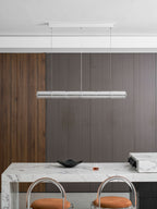 Small Clérachic glass chandelier, switched off, hanging from a white ceiling canopy over a marble bar with orange stools.