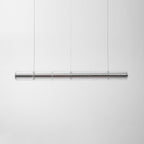 Clear segmented glass chandelier from Clérachic hung on thin cables against a soft grey backdrop, shown unlit.