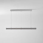 This Clérachic glass chandelier hangs from a chrome ceiling bar on three cables, shown unlit against a pale grey wall.