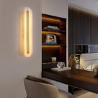 Clérachic Selvia wall light glowing beside a walnut desk and an open shelving unit.