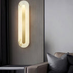 Clérachic Selvia wall light on a dark grey wall beside a leather sofa and cushions.