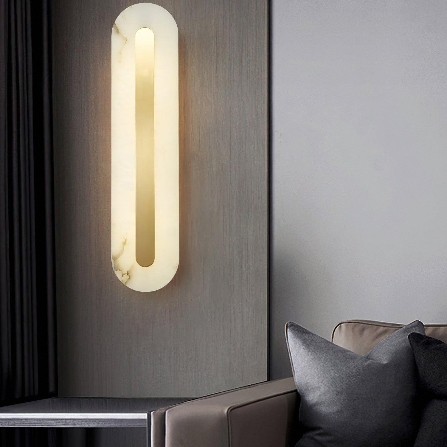 Clérachic Selvia wall light on a dark grey wall beside a leather sofa and cushions.