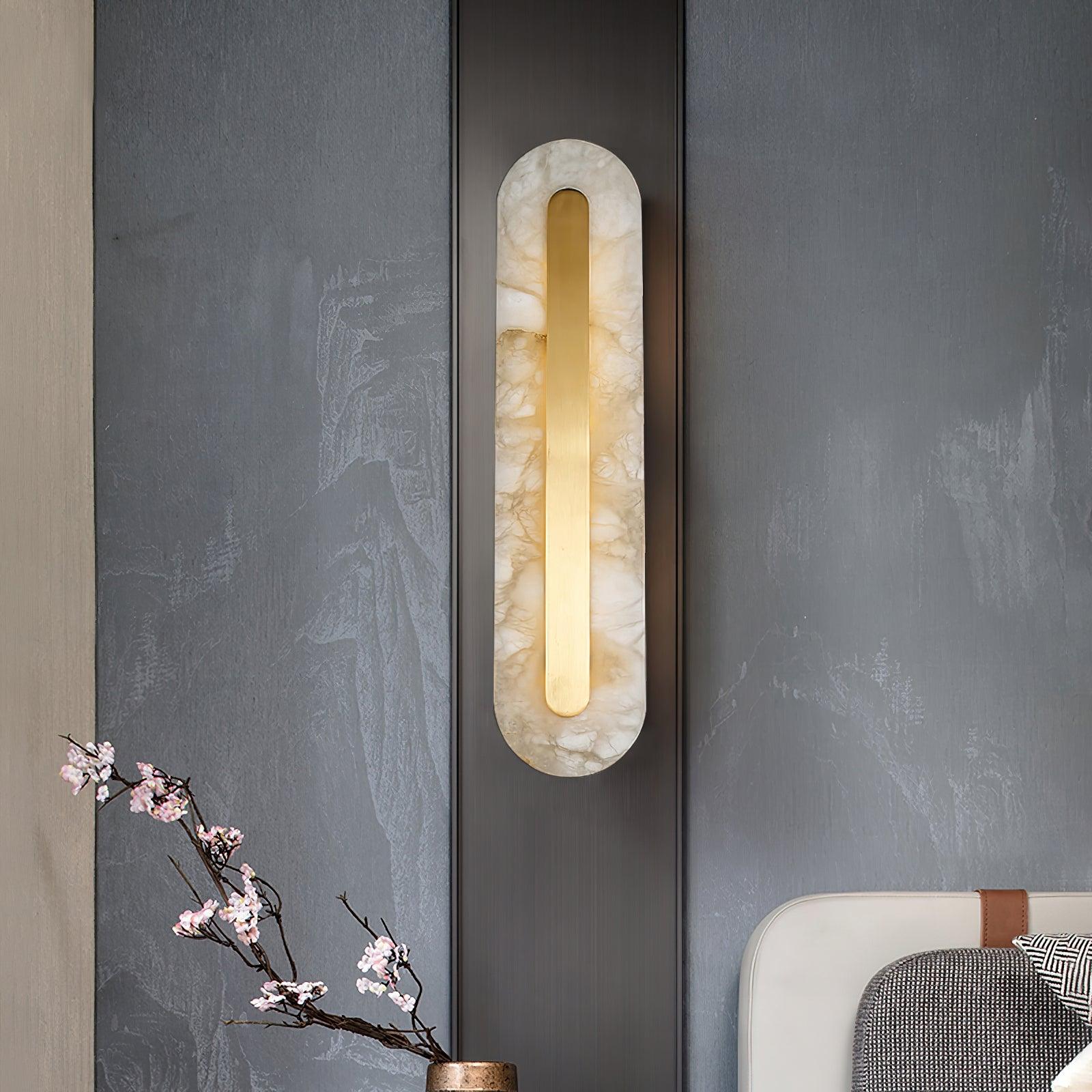 Clérachic Selvia sconce on a grey concrete wall beside a branch of cherry blossom.