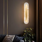 The Clérachic Selvia sconce on a dark brown wall above a sofa and potted plant.