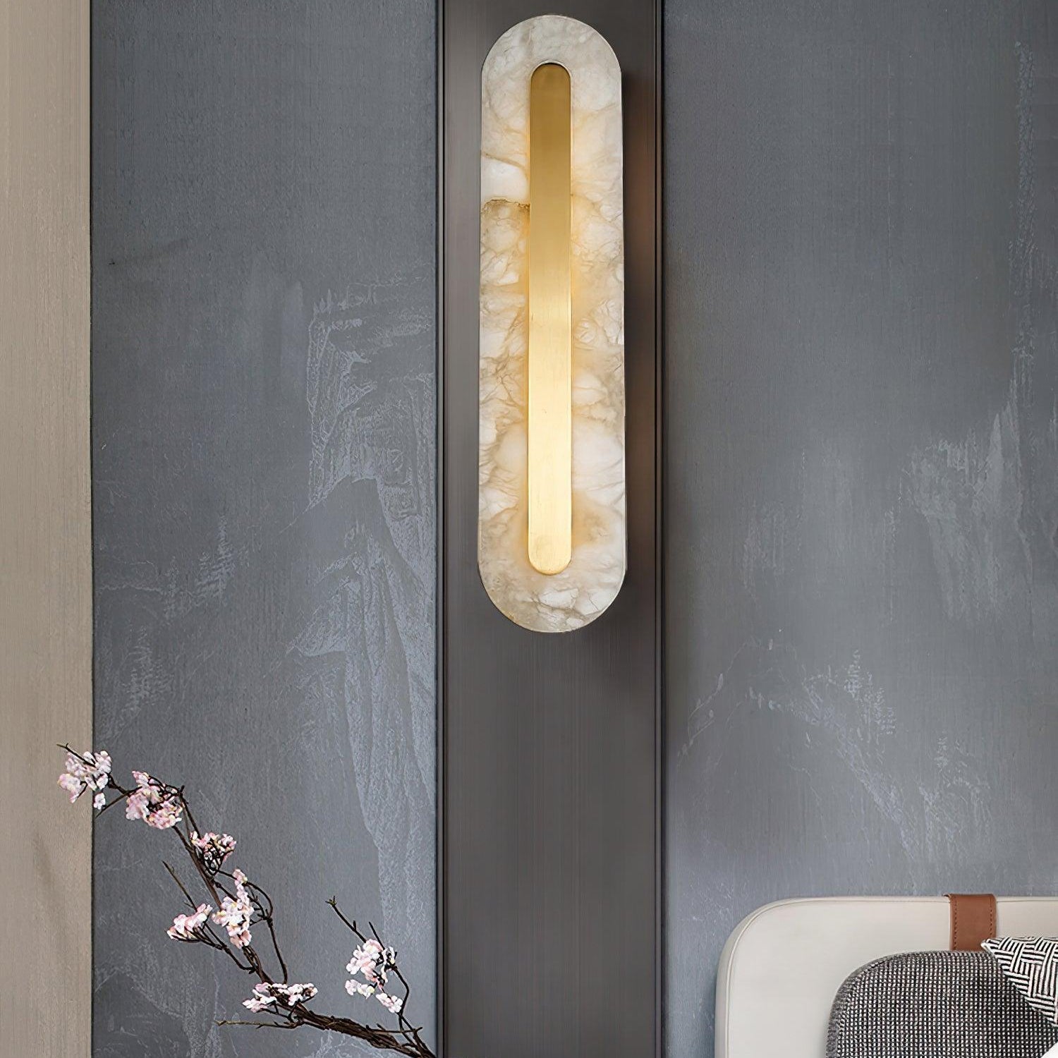 Clérachic Selvia wall light on a slate wall beside blossom in a vase and a bed.