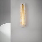 Clérachic Selvia sconce lit on a soft white wall next to a curved plaster form.
