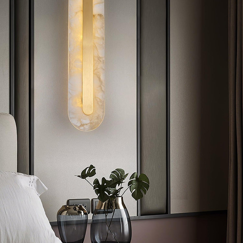 Clérachic Selvia wall light lit beside a bed with a black window frame and glass vases.